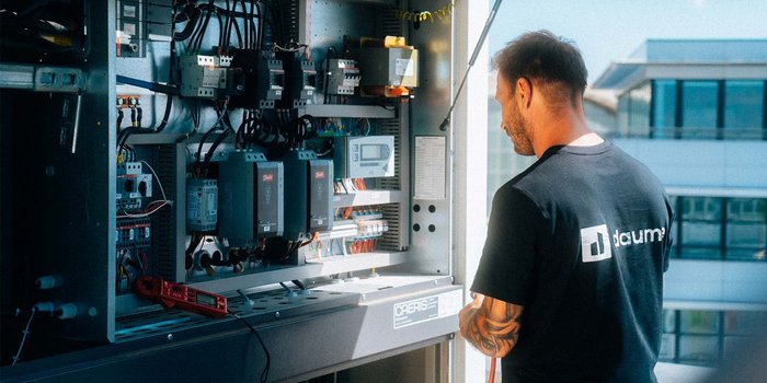 Ein Techniker arbeitet konzentriert an einem Schaltschrank, um elektrische Komponenten zu überprüfen und zu warten.