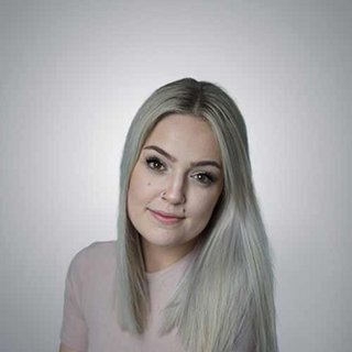 Die Frau hat einen freundlichen Ausdruck und trägt ein schlichtes, helles Oberteil, das ihre natürliche Schönheit betont.